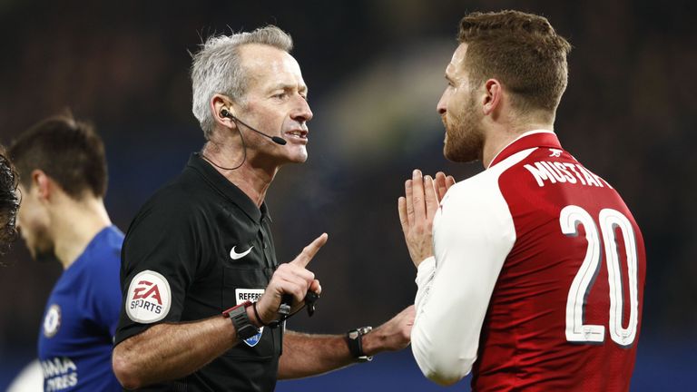 English referee Martin Atkinson (L) speaks with Arsenal's German defender Shkodran Mustafi during the English League Cup semi-final first leg football matc