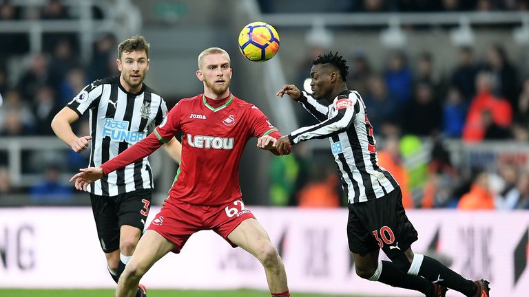 NEWCASTLE UPON TYNE, ENGLAND - JANUARY 13:  Christian Atsu of Newcastle United wins a header over Oliver McBurnie of Swansea City during the Premier League