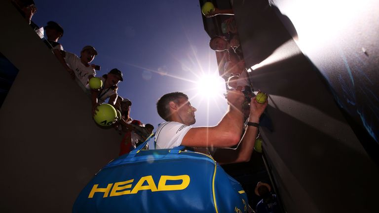 Novak Djokovic of Serbia signs autographs for fans after winning his first round match against Donald Young