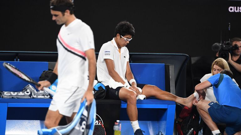 South Korea's Hyeon Chung receives medical attention against Switzerland's Roger Federer (L) during their men's singles semi-finals match