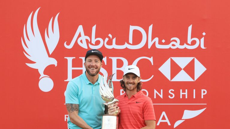 Tommy Fleetwood of England celebrates with the winner's trophy and caddie Ian Finnis after the final round of the Abu Dhabi Championship