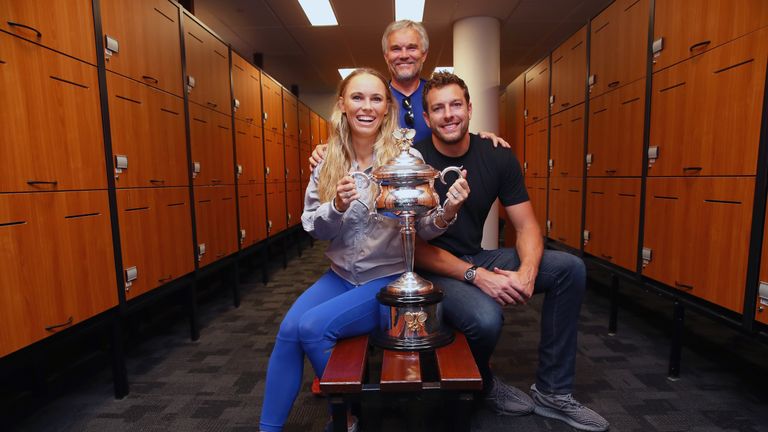Caroline Wozniacki of Denmark poses with fiance David Lee and father Piotr with the Daphne Akhurst Trophy in the locker room