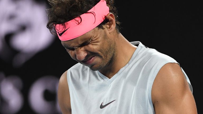 Rafael Nadal grimaces as he walks on court while preparing to serve to Croatia's Marin Cilic during their men's singles quarter-finals