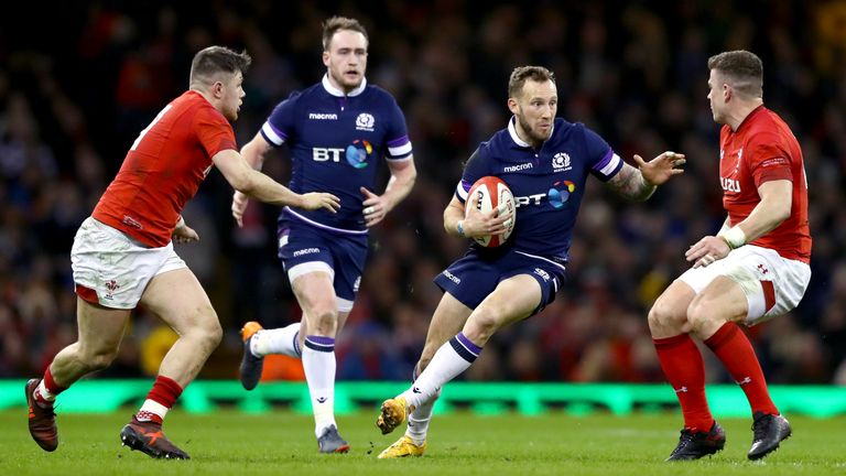 Byron McGuigan of Scotland runs with the ball towards Scott Williams of Wales