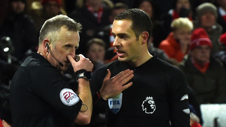Referee Jonathan Moss (L) discusses the first penalty with his assistant during the Premier League match between Liverpool and Tottenham at Anfield