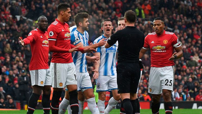 Players surround referee Stuart Attwell as they react after Manchester United's English midfielder Scott McTominay was injured in a collision withHuddersfi