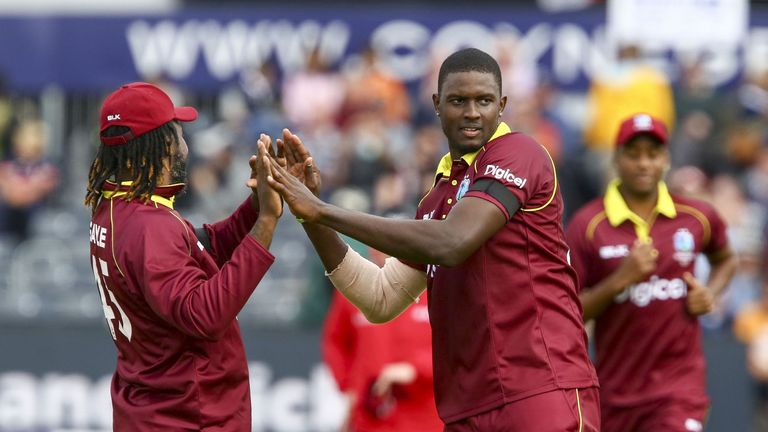 West Indies bowler Jason Holder celebrates with West Indies' Chris Gayle (L) after taking the wicket of England captain Eoin Morgan during the third one da