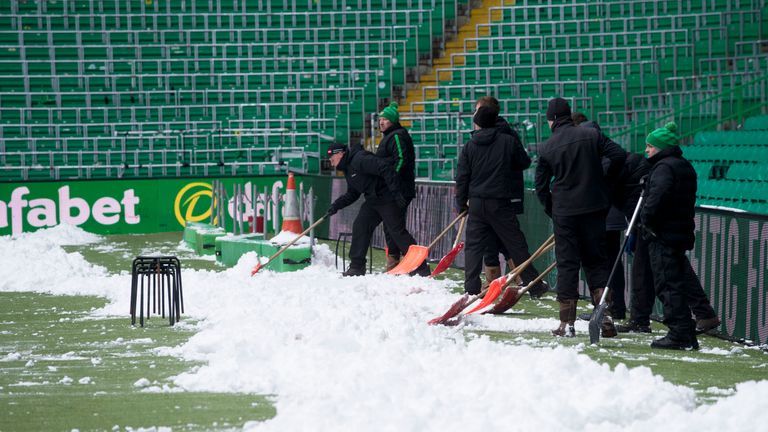 The Celtic ground staff work to clear the snow from the pitch ahead of Celtic's Scottish Cup tie against Morton