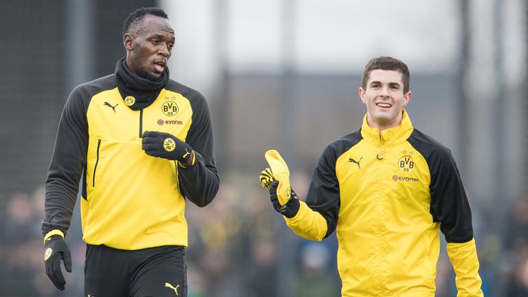 Usain Bolt talks to attacking midfielder Christian Pulisic during a Borussia Dortmund training session on March 23, 2018