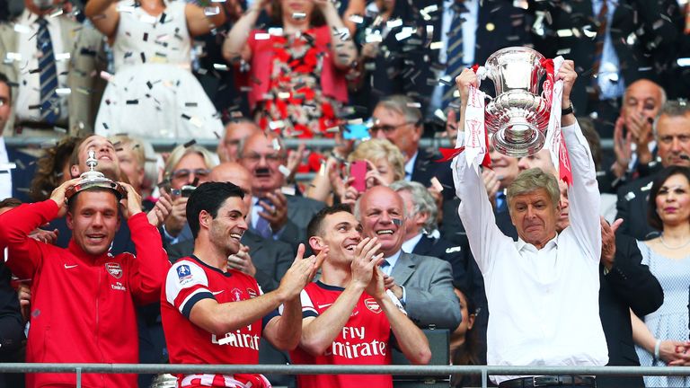 Arsene Wenger lifts the FA Cup alongside Lukas Podolski, Mikel Arteta and Thomas Vermaelen after the FA Cup Final victory over Hull City at Wembley Stadium on May 17, 2014