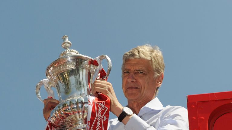 Arsene Wenger celebrates with the FA Cup onboard the Arsenal team bus during the FA Cup Victory Parade in Islington, London on May 18, 2014