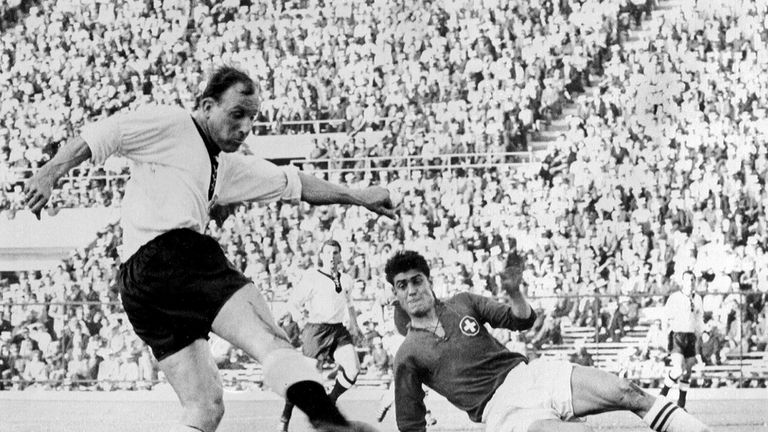 Swiss defender Heinz Schneiter attempts to block the shot of German forward Uwe Seeler