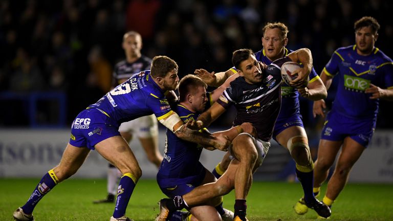 Joel Moon of Leeds is tackled by Daryl Clark and Mike Cooper of Warrington