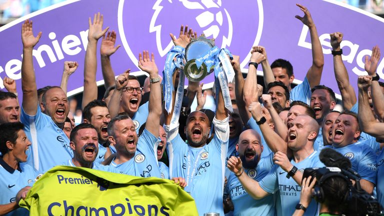 Pep Guardiola lifts the Premier League trophy surrounded by his backroom staff after Manchester City are crowned Premier League champions