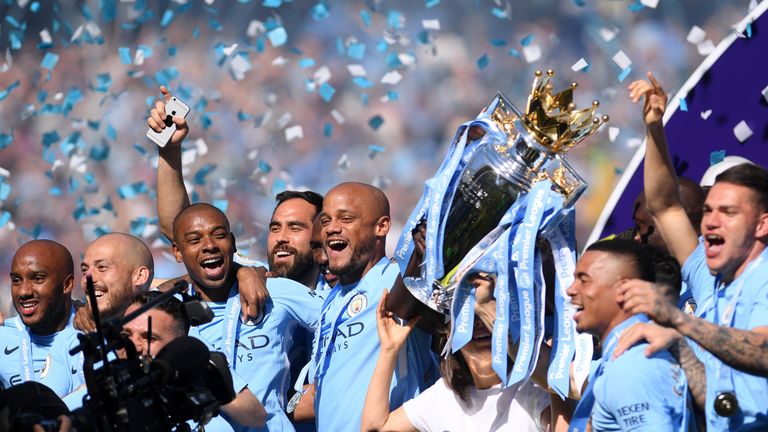 Vincent Kompany and his Manchester City teammates celebrate with the Premier League trophy as they're crowned champions at the Etihad Stadium