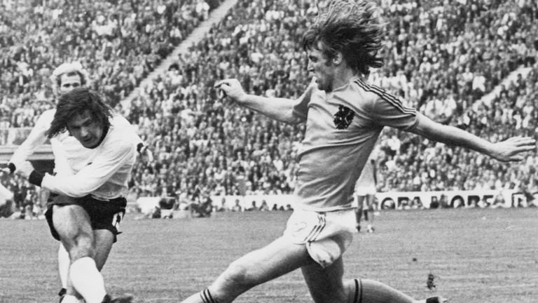 West German forward Gerd Muller (L) scores the second goal for his team despite the being pressured by Dutch defender Rudi Krol during the World Cup final
