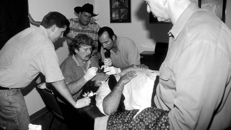 Jim Ross looks on as Foley is treated for his extensive injuries after the match