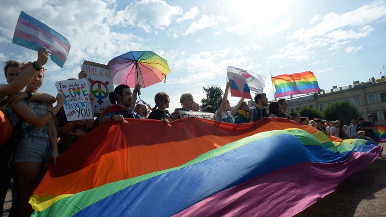 Activists in St Petersburg hold a rainbow flag during a Pride march, August 2017