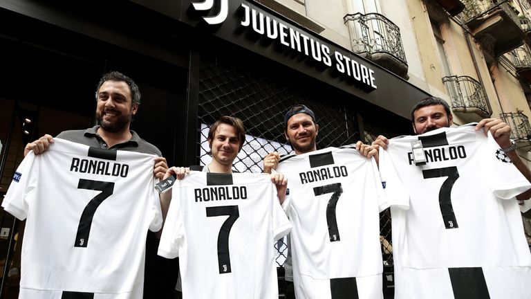 Juventus supporters pose with a Cristiano Ronaldo No.7 Jersey in front of the Juventus store on July 10, 2018