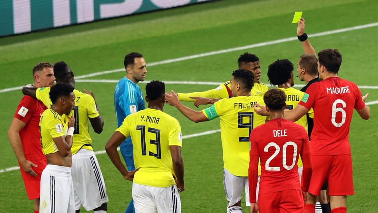 Referee Mark Geiger shows Colombia's Wilmar Barrios a yellow card for head butting England's Jordan Henderson