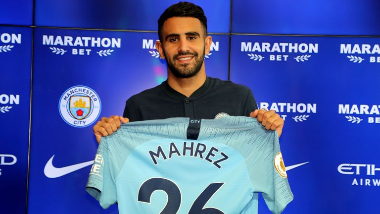 New Manchester City signing Riyad Mahrez holds up his shirt during the press conference at the City Football Academy