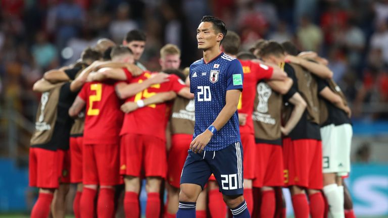 Tomoaki Makino of Japan walks dejectedly past Belgium players in a huddle following the final whistle
