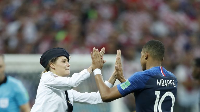 A pitch invader high fives Kylian Mbappe