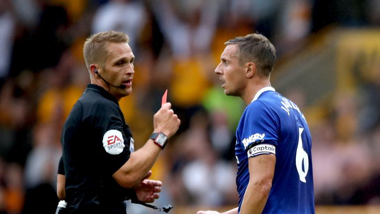 Referee Craig Pawson shows a red card to Phil Jagielka for a tackle on Diogo Jota (not pictured)