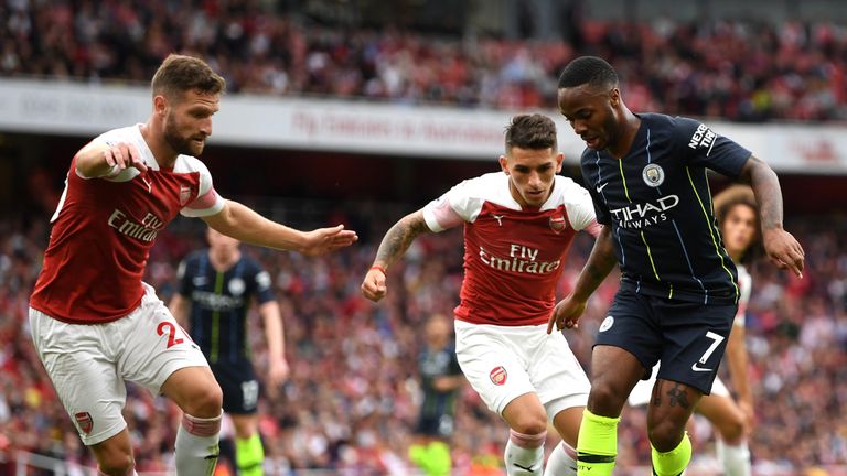 Raheem Sterling runs with the ball under pressure from Shkodran Mustafi and Lucas Torreira