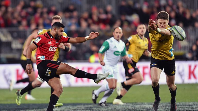 The Crusaders' Richie Mo'unga clears the ball under pressure from the Hurricanes' Beauden Barrett