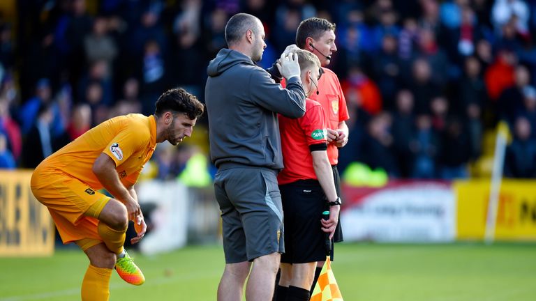 Assistant referee Calum Spence receives treatment for a head wound after an object appeared to be thrown