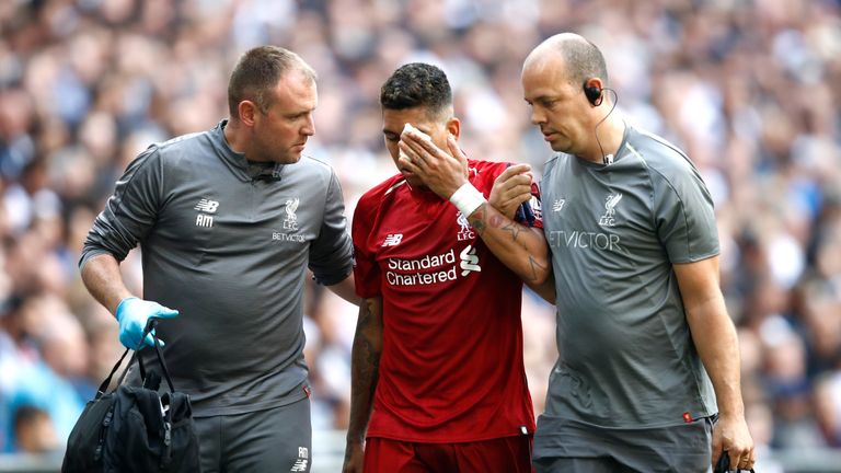 Roberto Firmino is led away by Liverpool medical staff after injuring his eye in 2-1 win over Tottenham at Wembley