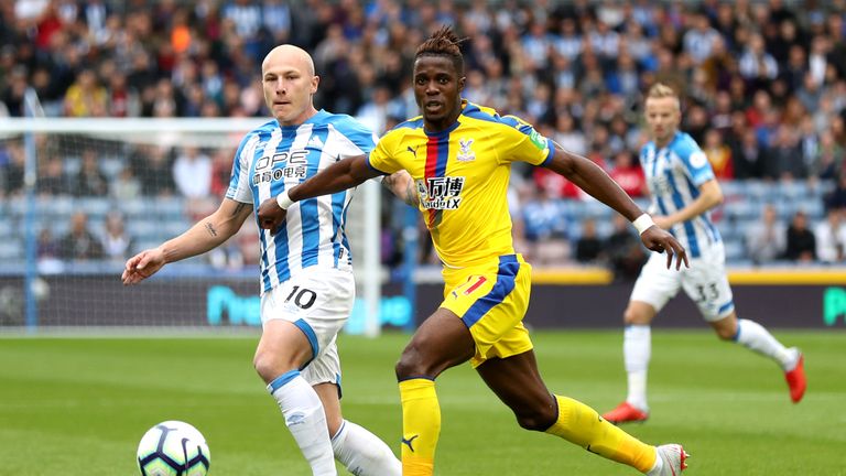 Wilfried Zaha battles for the ball with Aaron Mooy