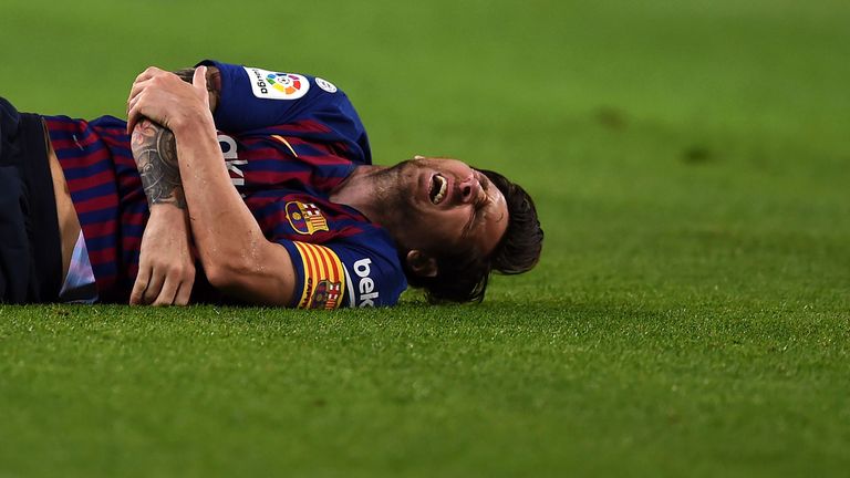 Lionel Messi clutches his injured arm