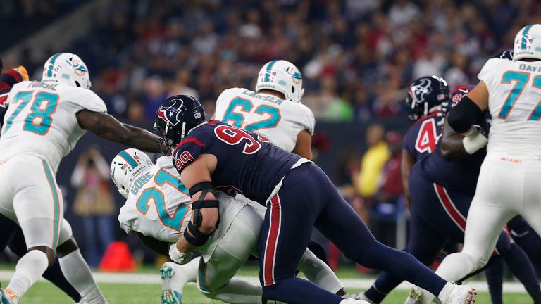 J.J. Watt #99 of the Houston Texans tackles Frank Gore #21 of the Miami Dolphins for a loss in the first quarter at NRG Stadium on October 25, 2018 in Houston, Texas.