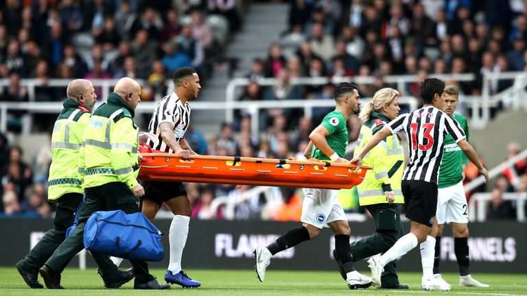 Players help paramedics carry a stretcher following a clash of head between Glenn Murray and Federico Fernandez