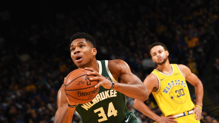 Giannis Antetokounmpo shoots a free throw as a frustrated Stephen Curry looks on