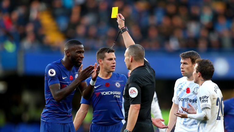 Referee Kevin Friend shows Antonio Rudiger a yellow card