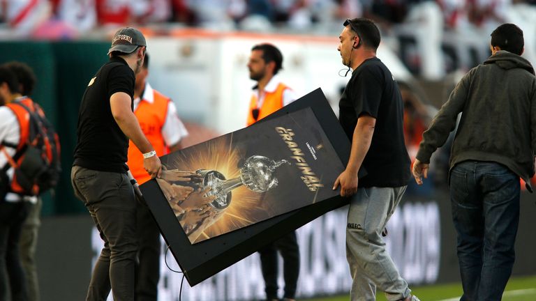 Organisers remove a sign from the Estadio Monumental pitch after the Copa Libertadores was postponed on Saturday
