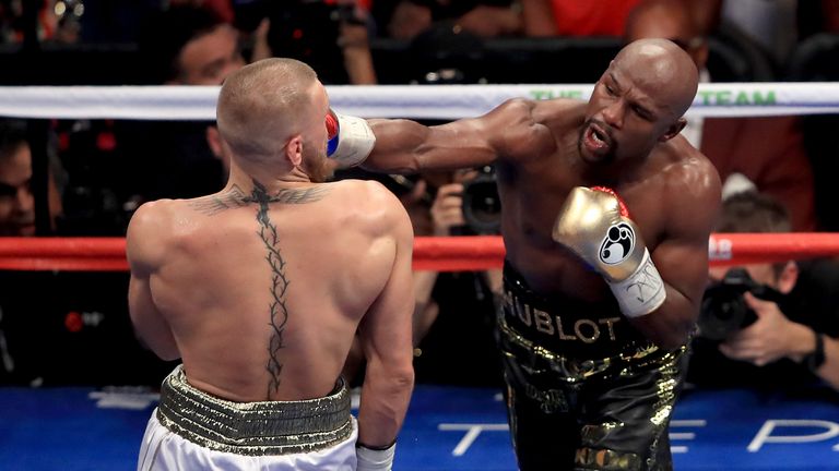 (L-R) Floyd Mayweather Jr. throws a punch at Conor McGregor during their super welterweight boxing match on August 26, 2017 at T-Mobile Arena in Las Vegas, Nevada.