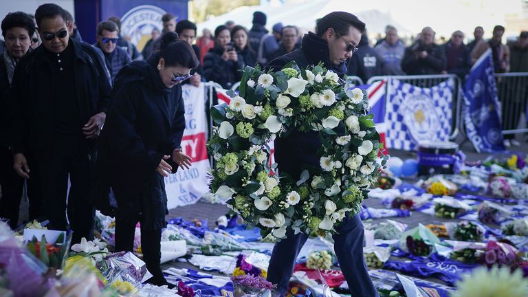 iyawatt Srivaddhanaprabha (R) and Aimon Srivaddhanaprabha (C), the son and wife of Leicester City owner Vichai Srivaddhanaprabha who died in a helicopter crash at the club's stadium, pray after laying wreathes among the sea of tributes to the victims of the crash at Leicester City Football Club's King Power Stadium
