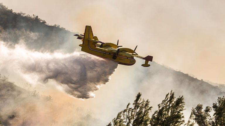 An airplane drops water on wildfires close to the 101 Freeway in Thousands Oaks, California