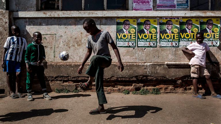 A group of boys play football in front of electoral posters in support of Presidential candidate Emmerson Mnangagwa at the suburb of Mbare in Zimbabwe&#39;s capital Harare on July 27, 2018, prior to the upcoming July 30, presidential election. - Mbare is a high-density suburb and one of the poorest areas of Harare and was known for being a former president Robert Mugabe&#39;s stronghold