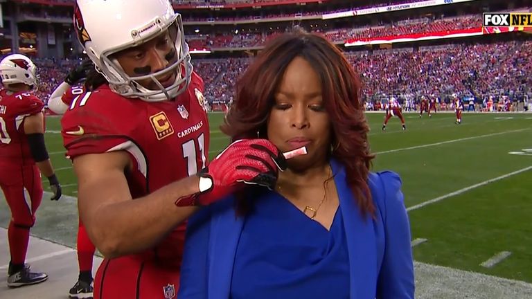 Larry Fitzgerald helps Fox reporter get ready for the camera by sneaking smelling salts by her nose.