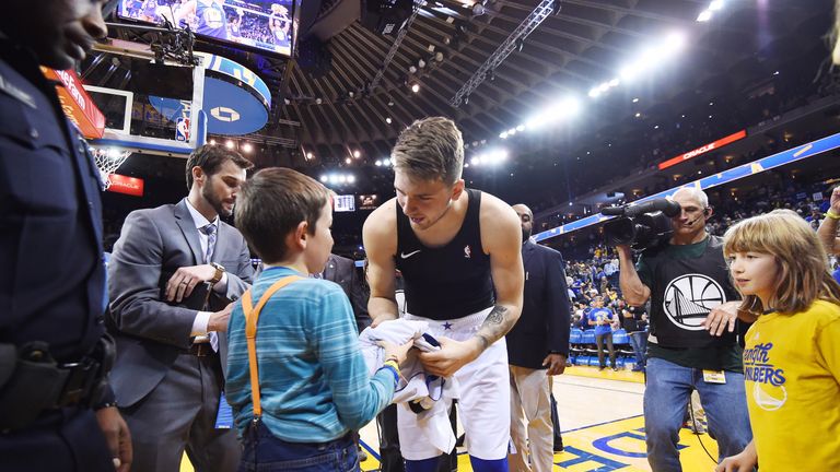 Luka Doncic gives his shirt to a young fan he fell on