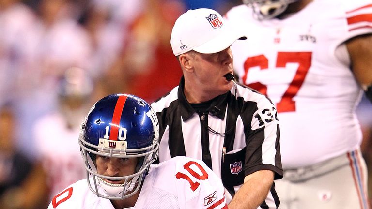 Referee John Parry #132 helps up quarterback Eli Manning #10 of the New York Giants after getting sacked for a loss on third down by Mark Anderson #95 of the New England Patriots in the first quarter during Super Bowl XLVI at Lucas Oil Stadium on February 5, 2012 in Indianapolis, Indiana.