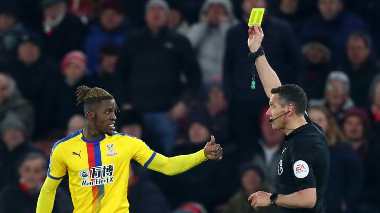Wilfried Zaha gestures toward match referee Andre Marriner after being shown a yellow card
