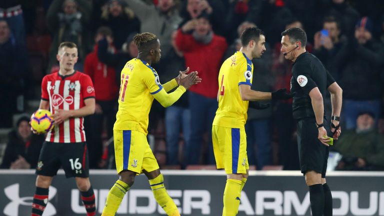 Wilfried Zaha applauds match referee Andre Marriner after being shown a yellow card