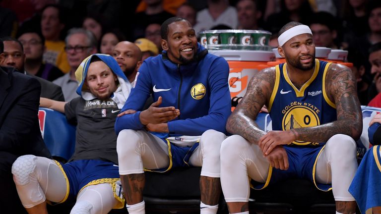 Stephen Curry, Kevin Durant and DeMarcus Cousins watch on from the bench against the LA Lakers