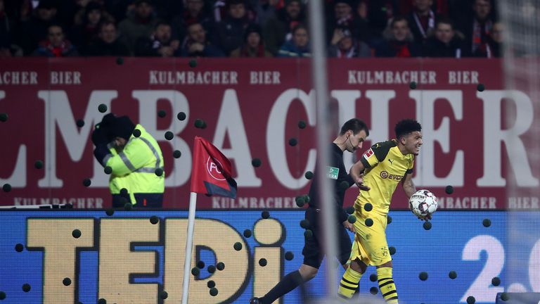 Tennis balls rain down on the pitch near Jadon Sancho in protest at the Monday night fixture